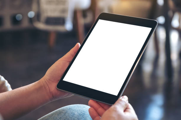 istock Mockup image of hands holding black tablet pc with blank white screen while sitting in cafe 1071259918