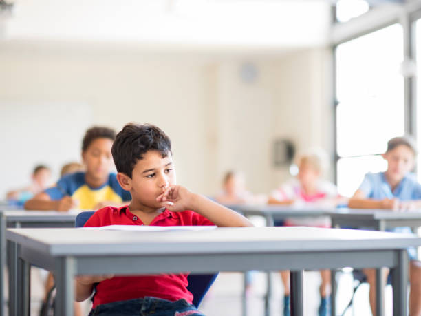 istock Thoughtful little boy sitting in school 1071267760