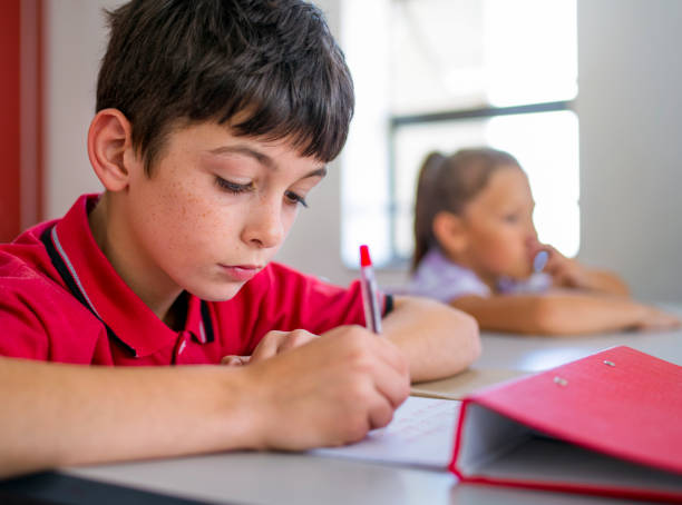 istock Schoolboy writing on paper in elementary school 1071269490
