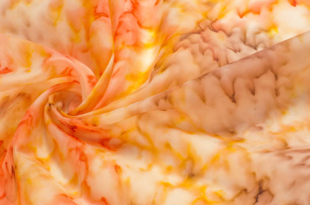 istock Texture, background, pattern. Silk fabric with a blurry red yellow pattern. Yellow, red and cream flowers on white 1071269868