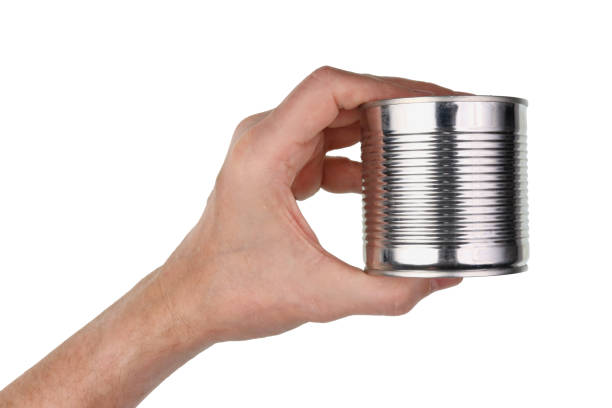 An elderly man holds in his hand a closed can of canned food. Isolated stock photo