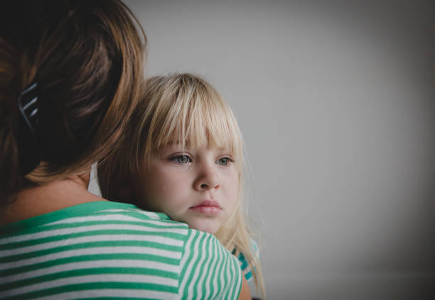 sad crying little girl hugging mother, parenting stock photo