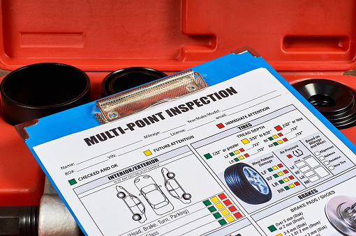 Vehicle multi-point inspection form against the background of automotive tools. Close up.