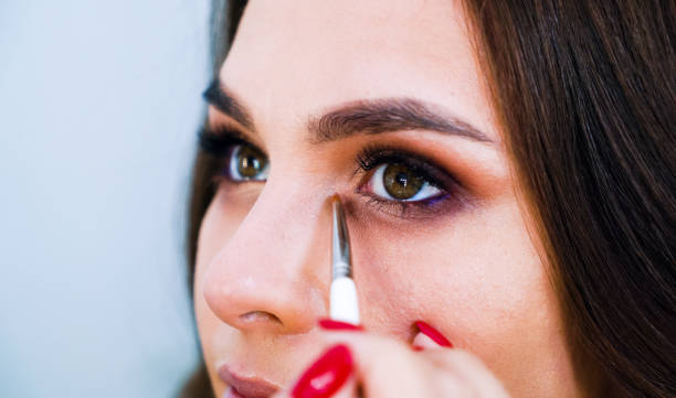 istock Closeup female hands applying eyeshadows on cute young woman's eyelids using special brush 1071298940