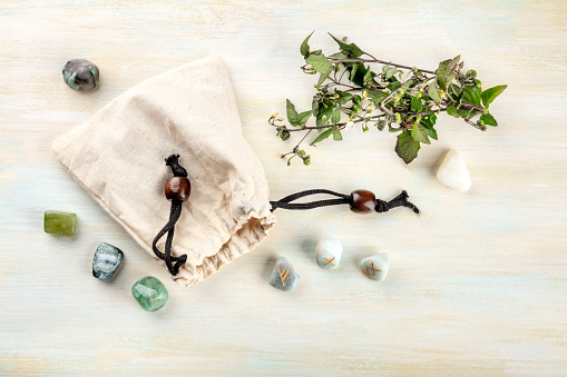 Runes, stones with symbols used in Wicca and other magic and for divination, tossed from a bag, shot from the top on a light background with crystals and a place for text