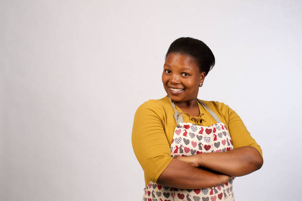 hermosa mujer africana con delantal brazos cruzados sonriendo - deep etch fotografías e imágenes de stock