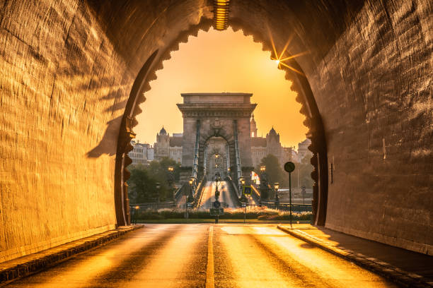 budapest, ungarn - eingang des buda tunnels bei sonnenaufgang mit leeren széchenyi kettenbrücke mit sonnenstrahlen - alagut stock-fotos und bilder