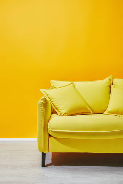 istock Sofa with pillows near bright yellow wall 1071308816