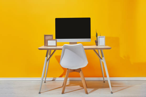 istock Computer, photo frames and cactus at workplace near  yellow wall 1071309010