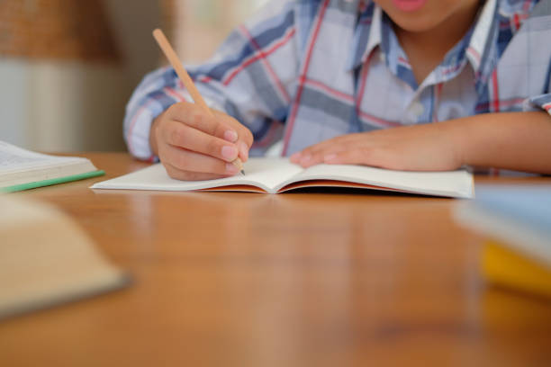 istock little asian kid boy schoolboy writing drawing on notebook. child children doing homework. 1071310862