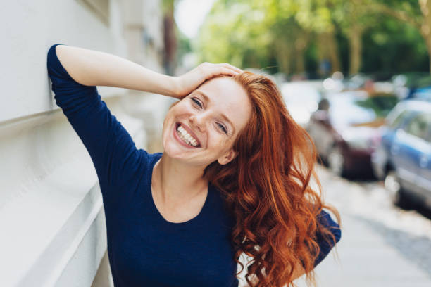 Happy friendly young woman leaning on a building
