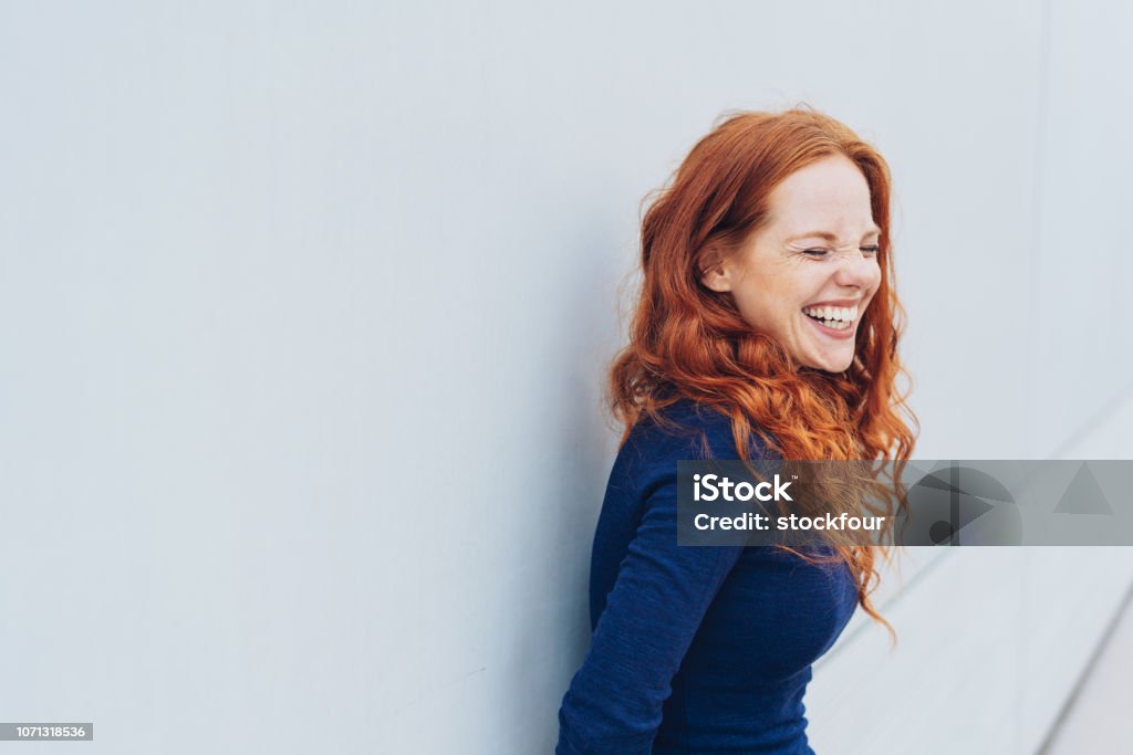 Attraente giovane donna in piedi ridacchiando - Foto stock royalty-free di Donne