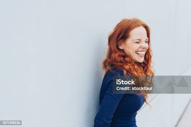 Attraente Giovane Donna In Piedi Ridacchiando - Fotografie stock e altre immagini di Donne - Donne, Solo una donna, Sorridere