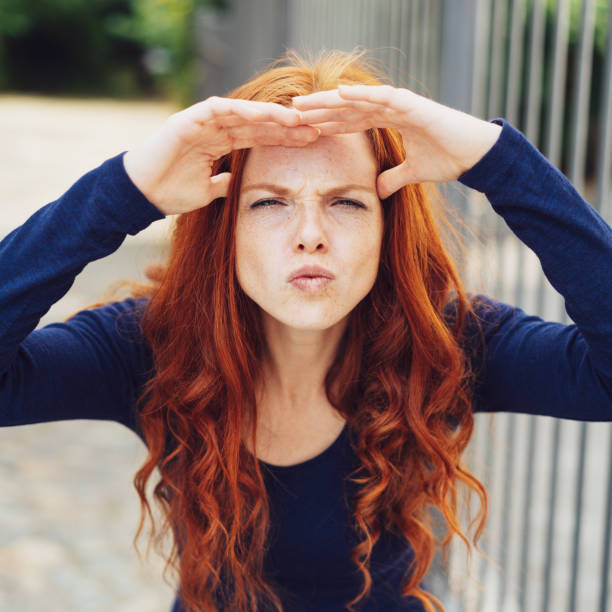 istock Young woman squinting while shading her eyes 1071322382