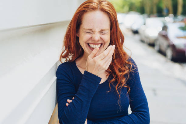 Woman covering her mouth while she laughs stock photo