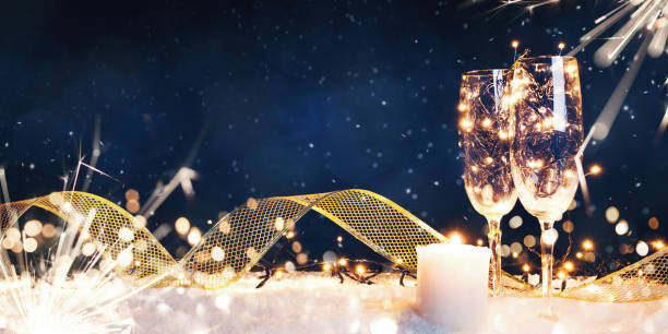 Two glasses filled with garlands with a candle and a gold ribbon in the snow Two glasses filled with garlands with a candle and a gold ribbon in the snow. Christmas card gala stock pictures, royalty-free photos & images