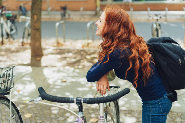 istock Attractive redhead woman leaning on her bicycle 1071327128