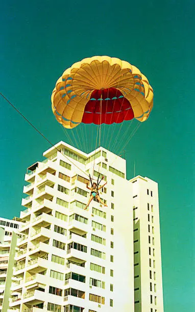 Vintage image of a woman flying in parachuting during a summer vacation in the seventies / eighties.