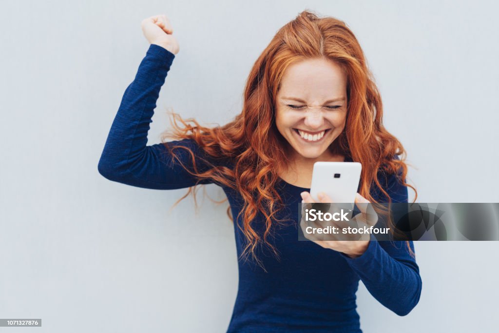 Jeune rousse célébrer la bonne nouvelle - Photo de Téléphone mobile libre de droits