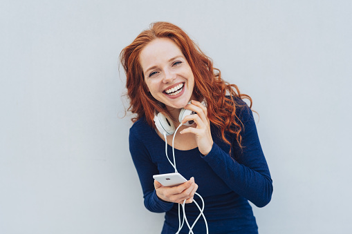 Happy adult woman with red hair and blue long sleeved shirt laughing while looking straight at camera