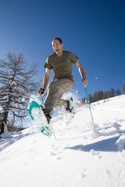 lächelnder mann wandern mit schneeschuhen im schnee - snowshoeing snowshoe women shoe stock-fotos und bilder