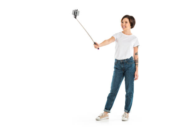 istock beautiful young woman taking selfie on smartphone using selfie stick isolated on white 1071330610