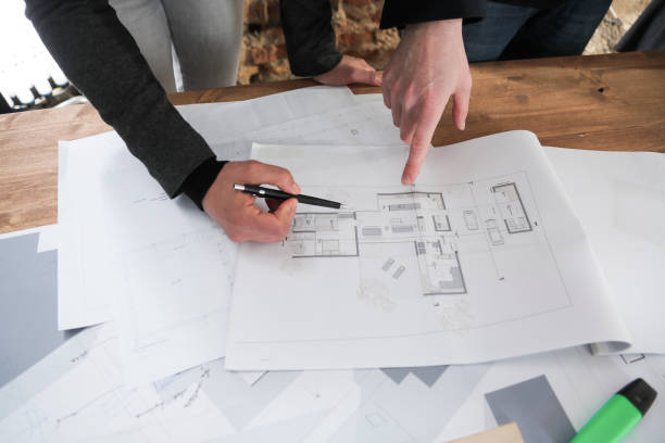 istock Man and woman looking at plans at construction site closeup 1071333886