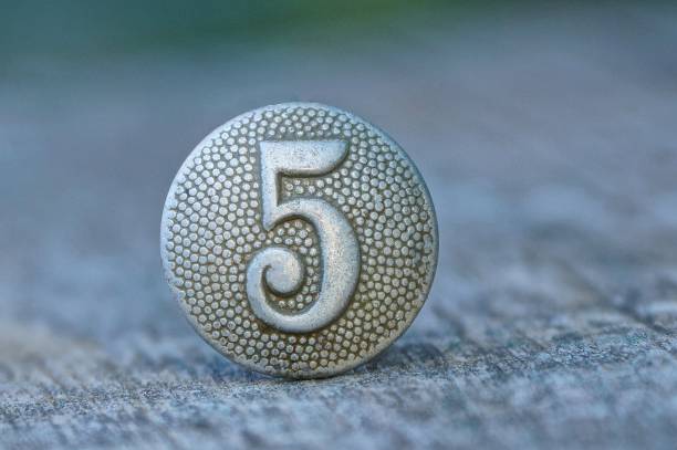 un vecchio pulsante grigio con il numero cinque su un tavolo di legno - brass buttons foto e immagini stock