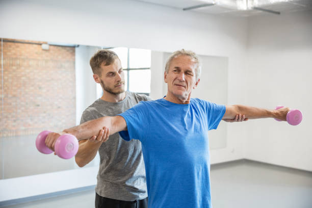 istock Senior man exercising with dumbbells with trainer 1071341642