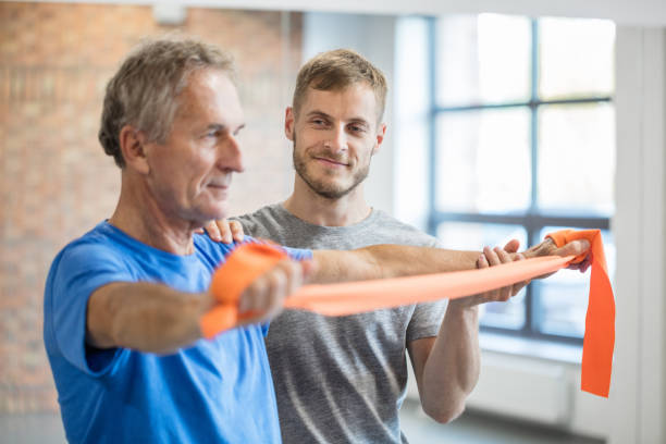istock Senior man exercising with instructor at rehab 1071341838