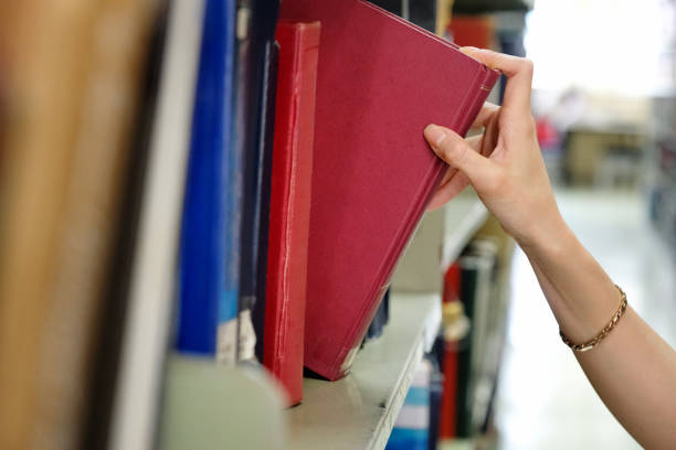 istock Young woman picking a book off the shelf in a library 1071346006