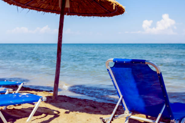 View on empty public beach with thatched sunshades, umbrellas and plastic deckchairs for a perfect holiday.