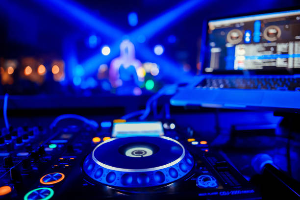 control DJ for mixing music with blurred people dancing at party in nightclub stock photo