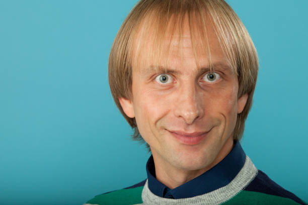 Studio portrait of a 35 year old blond man in a bright sweater on a blue background