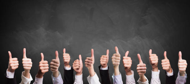 many thumbs up in front of a blackboard many thumbs up in business sleeves in front of a blackboard satisfaction stock pictures, royalty-free photos & images
