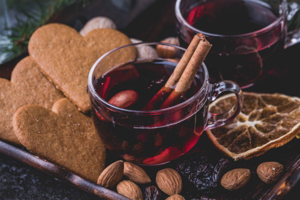 Mulled wine with heart shaped gingerbread cookies, almonds, raisins and dried sliced oranges. Mulled wine with cinnamon sticks. The glasses are on a dark wooden tray surronded by heart shaped traditional swedish gingerbread cookies, raisins, almonds and dried orange slices. Horizontal photo. mulled wine photos stock pictures, royalty-free photos & images