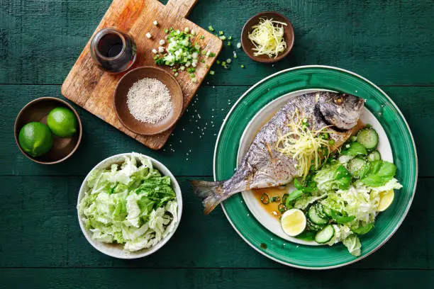 Grilled sea bream with fresh vegetables, herbs, ginger and Chinese broth