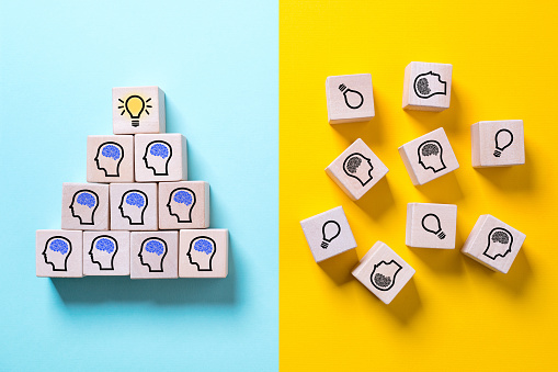 two colored sides symbolizing with icons on cubes a structured organization with innovation and a chaotic organization showing no progress