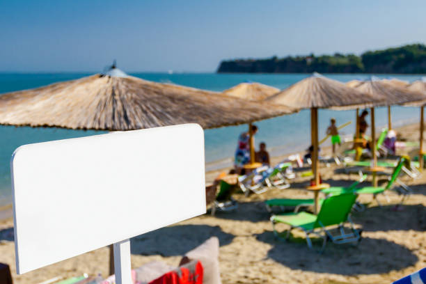 Information banner, colored wooden board is standing in front of public beach.