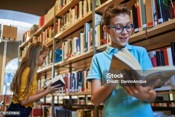 School Boy Reading A Book In The Library Stock Photo - Download Image Now - Library, 12-13 Years, Book