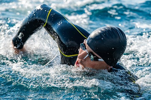 Male open water swimmer swimming forward crawl in sea.