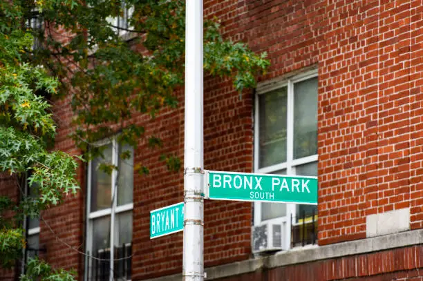 Bronx Park south sign and Bryant Avenue sing with a red building on background, Manhattan, New York city, USA.
