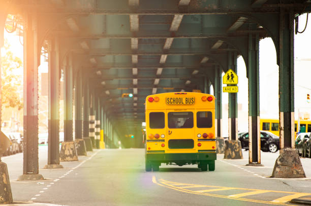 un autobús escolar está pasando bajo el puente del tren en el bronx, nueva york, estados unidos. - the bronx fotografías e imágenes de stock