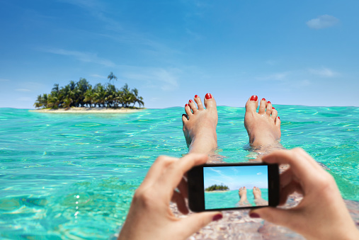 Woman is taking a picture on vacation with the smartphone. Photoshop compositing.