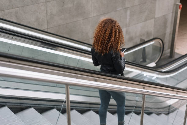 istock Woman with curly hair going down escalator 1071382608