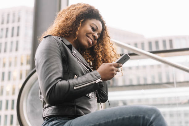 istock Young curly-haired black woman using mobile phone 1071383138