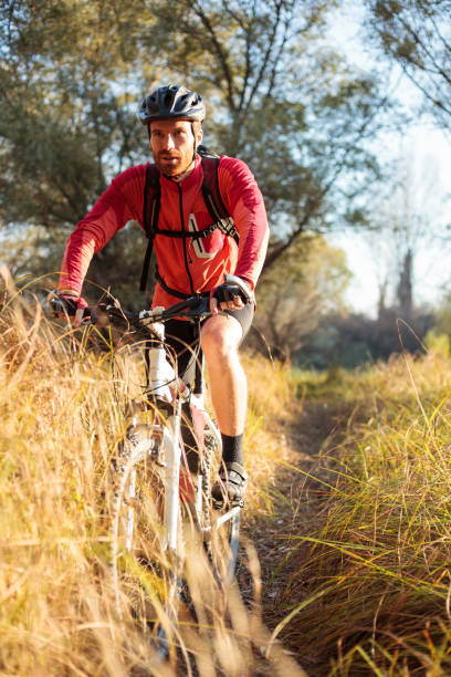 istock Determined young bearded man riding mountain bike along a path through tall grass 1071388716