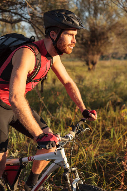 istock Focused young bearded man riding mountain bike along a path through forest 1071389316