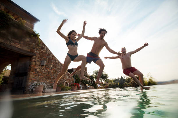 istock Friends Jumping into the Pool on Vacation 1071391236