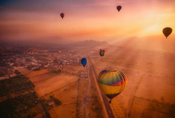 vista aérea de una escena de amanecer donde rayos de sol y globos de aire caliente llevan a turistas llenan el cielo colorido sobre pushkar, rajasthan, india. - heat mid air flying float fotografías e imágenes de stock